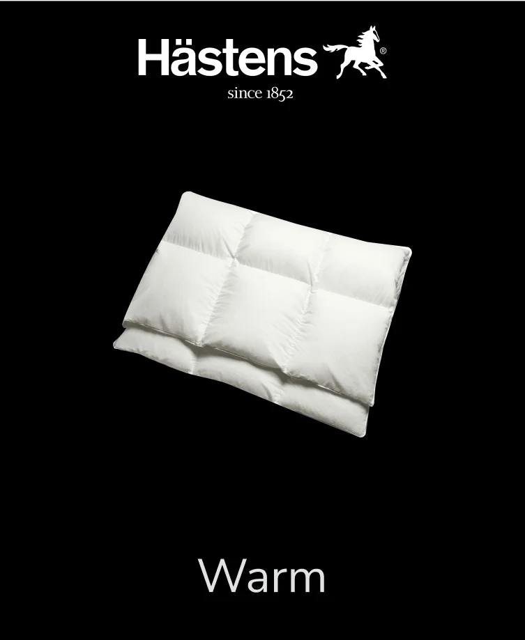 Thick, white Hastens Warm down comforter folded on a bed